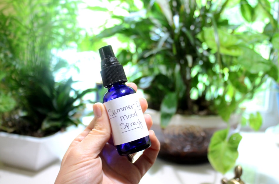 summer aromatherapy mood spray in hand with plants in background