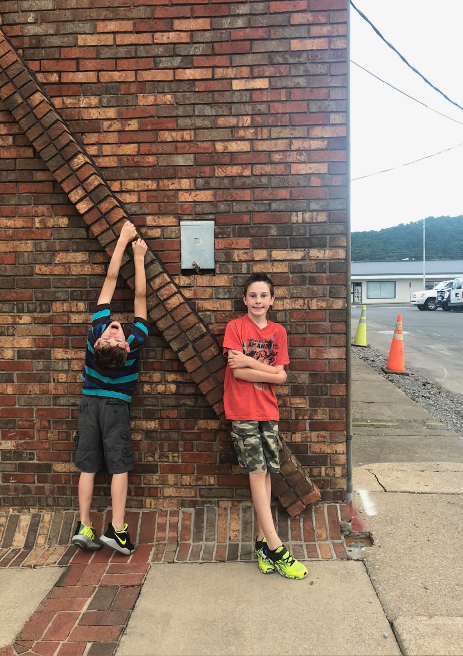 two boys next to a brick wall
