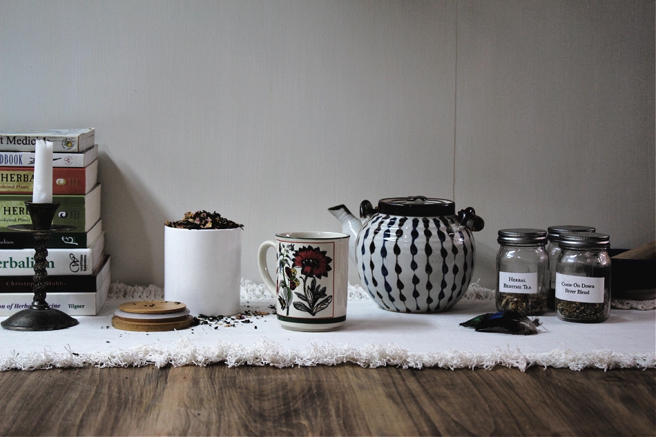 tea blends, teapot, books, and candle on table